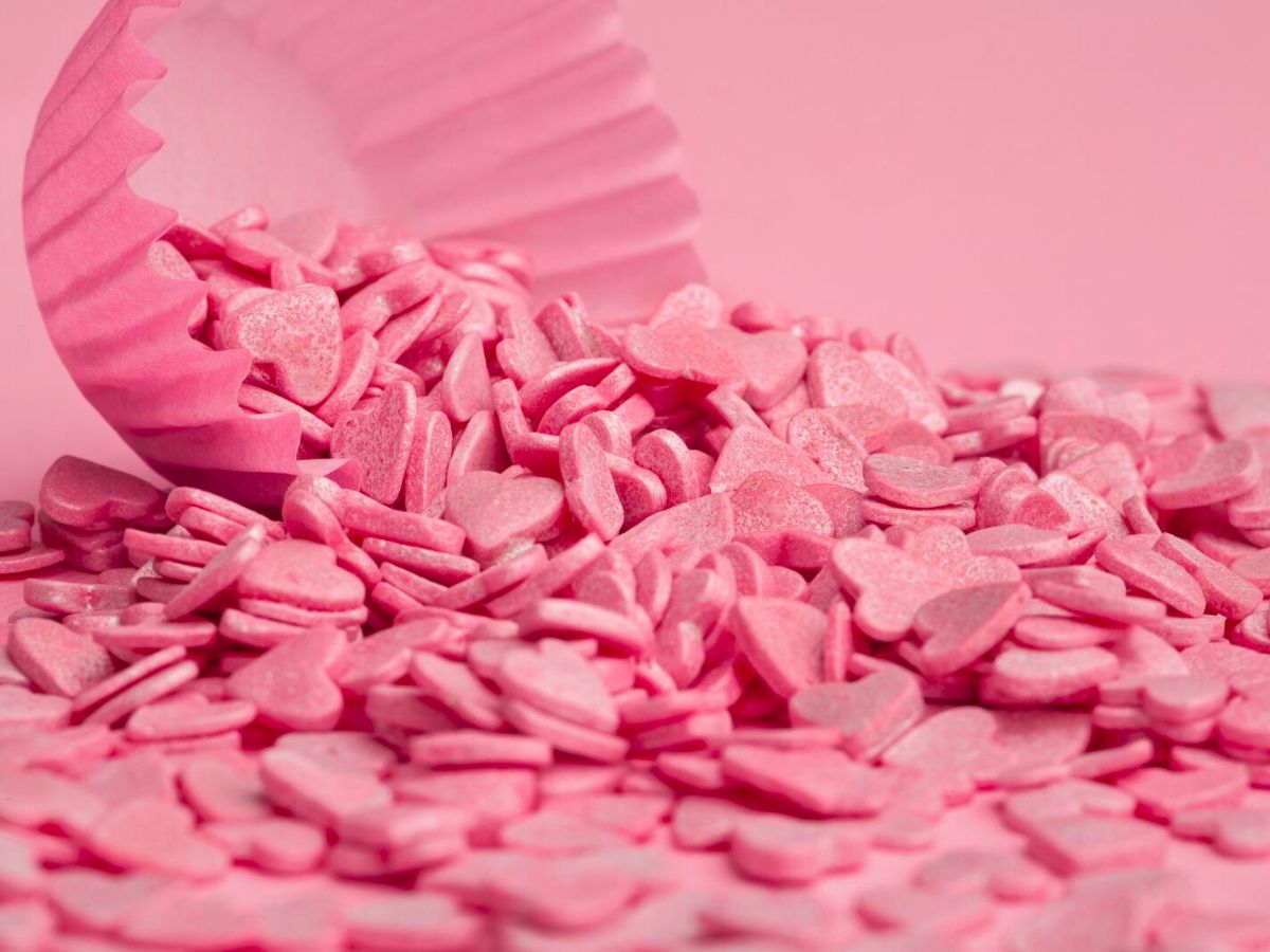 A pile of pink sprinkles on a pink background, perfect for adding a touch of sweetness to chocolate covered strawberries.