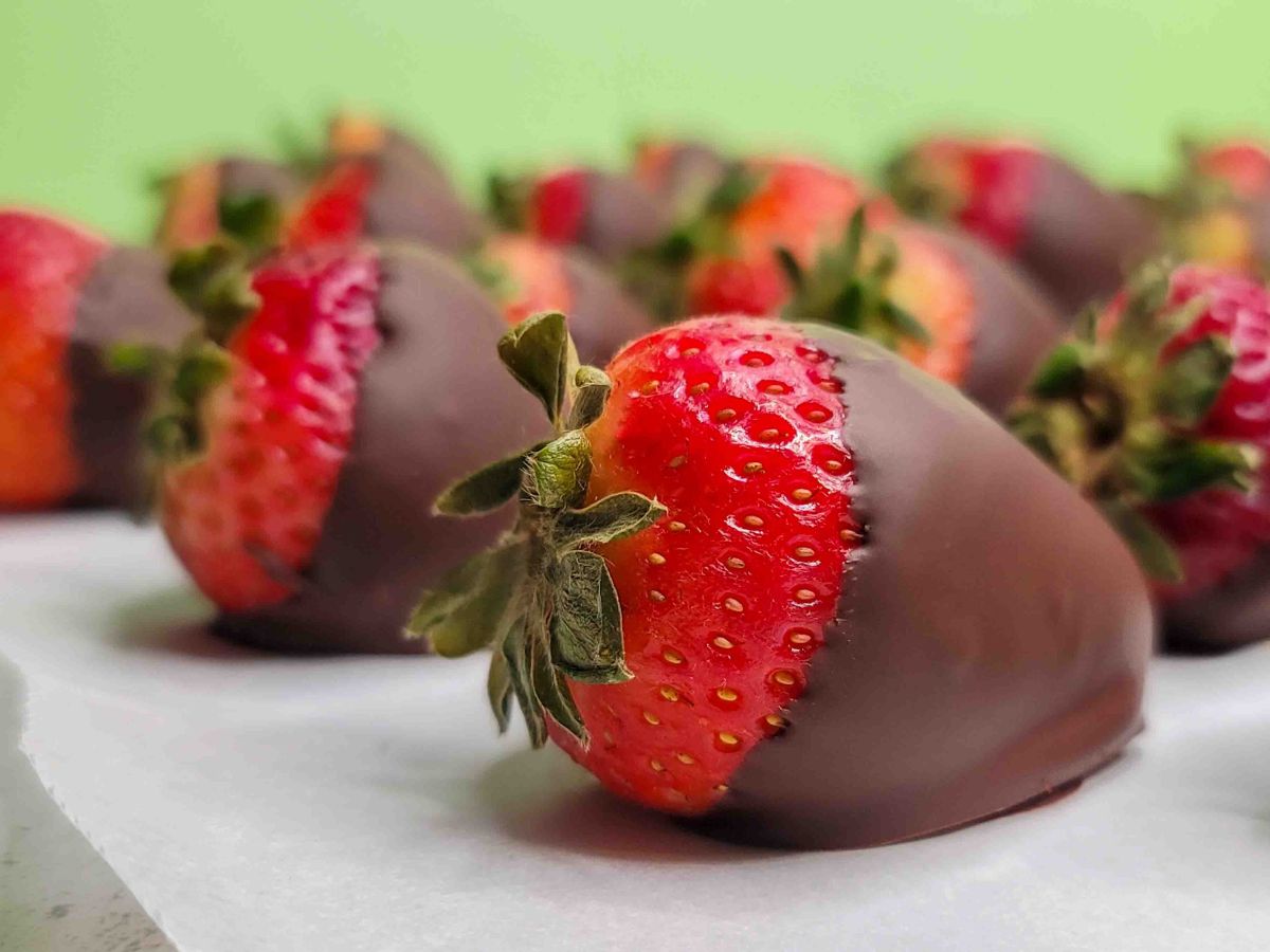 Rows of delicious chocolate covered strawberries on a sheet of parchment paper.