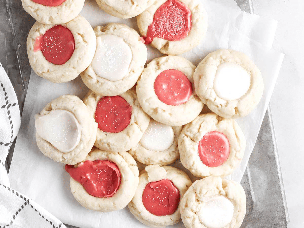Vegan thumbprint cookies in red and white on a white sheet of paper.