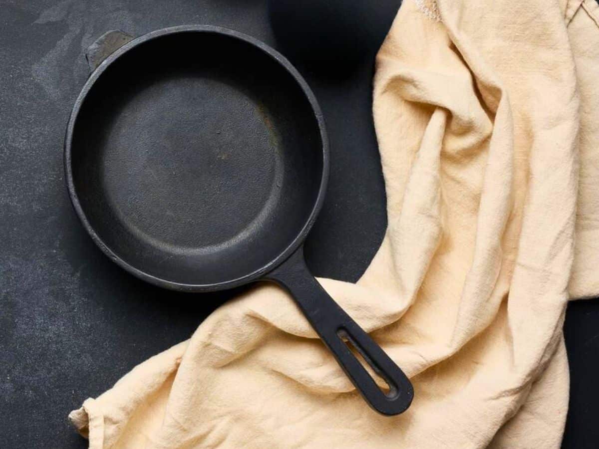 A dry cast iron skillet on a black surface.