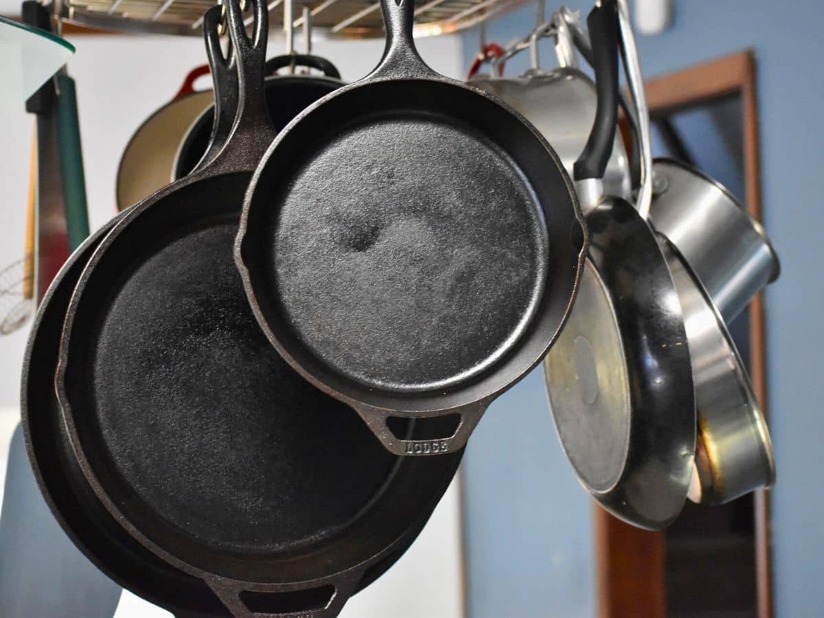 Cast iron pans hanging on a rack in a kitchen.