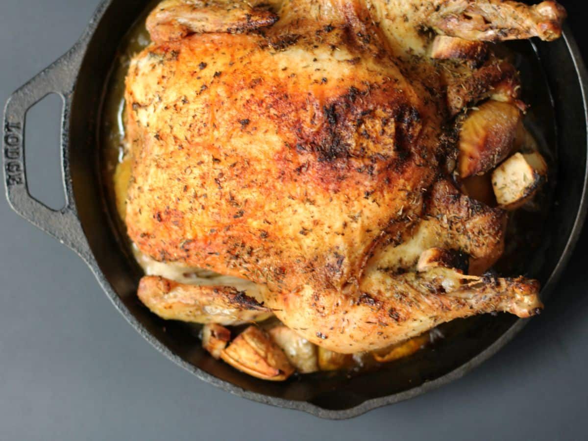 Roasted chicken with herbs in a cast iron skillet.
