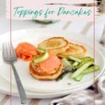 A plate of pancakes topped with smoked salmon and cucumbers, alongside grilled asparagus, set on a dining table with a festive graphic text overlay about toppings.